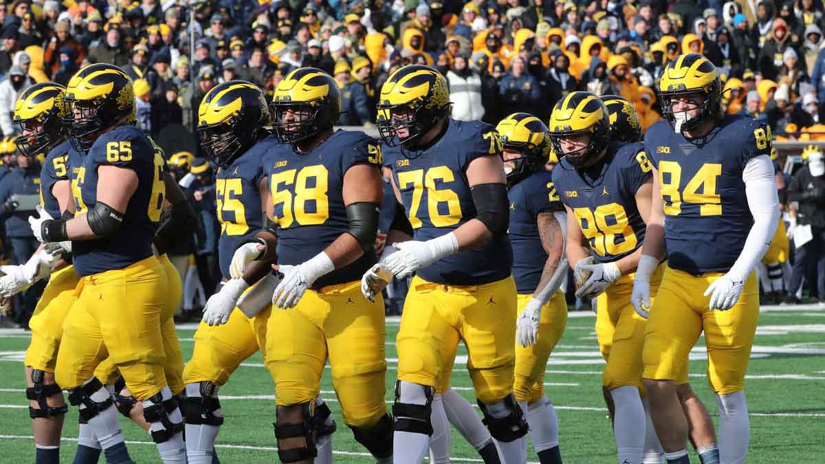 The Michigan Wolverines offensive line, including Zak Zinter (65), Olusegun Oluwatimi (55), Giovanni El-Hadi (58) and Ryan Hayes (76), and tight ends Matthew Hibner (88) and Joel Honigford, get set against the Illinois Fighting Illini