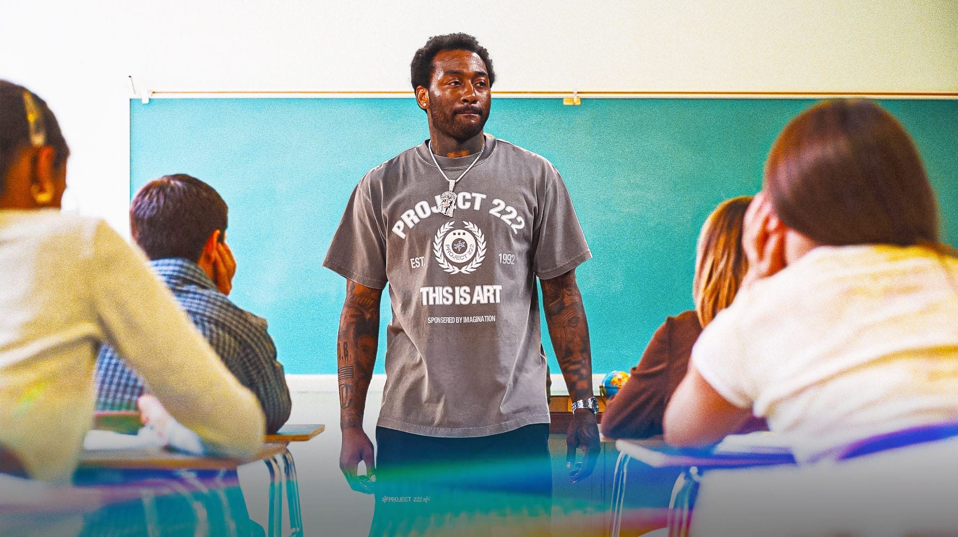 John Wall with a chalkboard behind him standing in front of students