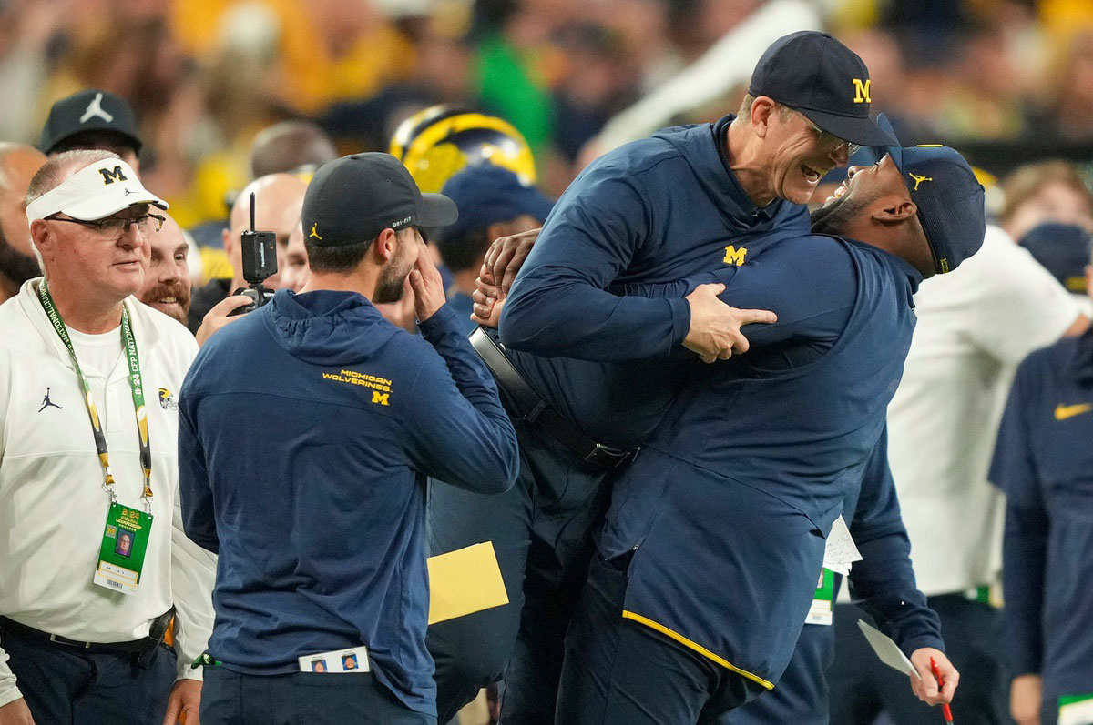 Michigan head coach Jim Harbaugh is lifted off the ground by offensive coordinator Sherrone Moore after Michigan won the College Football Playoff national championship game against Washington at NRG Stadium