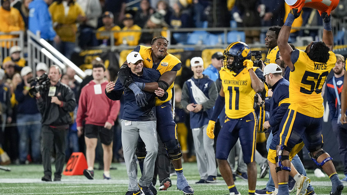 Dec 27, 2023; Charlotte, NC, USA; West Virginia Mountaineers head coach Neal Brown celebrates with his team after the win over North Carolina Tar Heels during the second half at Bank of America Stadium. Mandatory Credit: Jim Dedmon-USA TODAY Sports