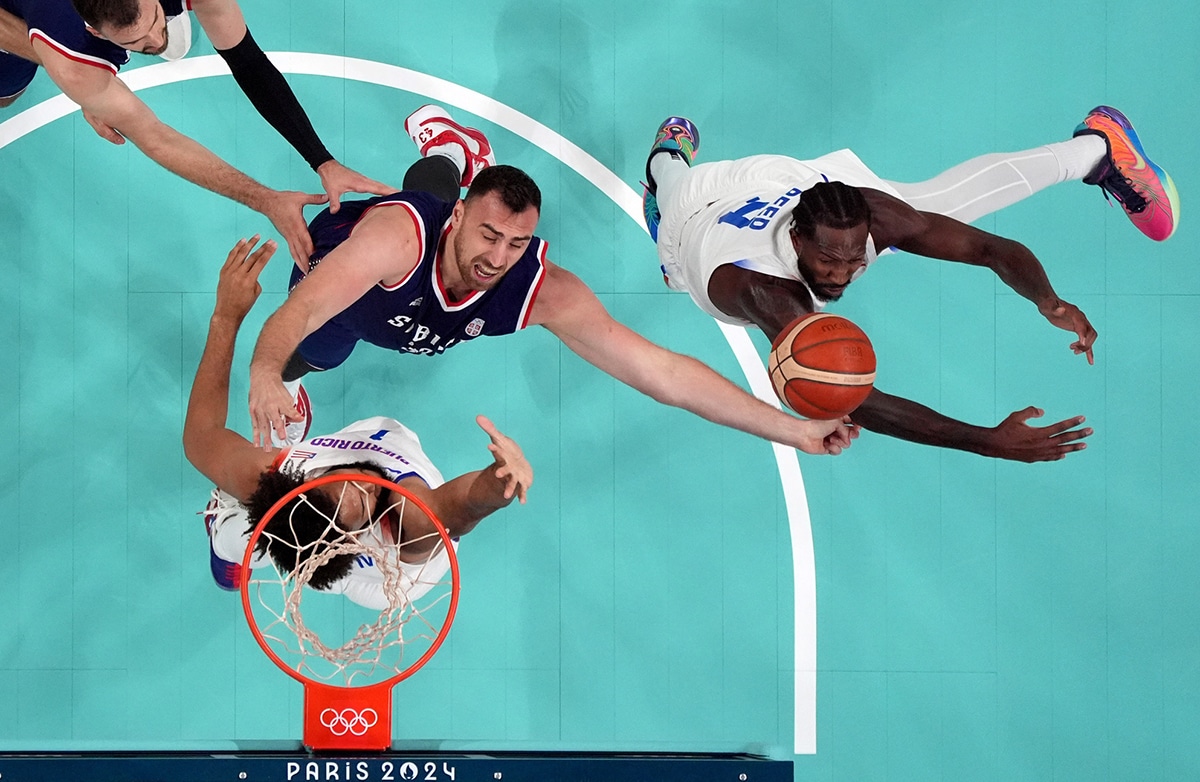 Puerto Rico shooting guard Davon Reed (9) blocks Serbia center Nikola Milutinov (33) in front of Puerto Rico forward George Conditt IV (1) in the second quarter during the Paris 2024 Olympic Summer Games at Stade Pierre-Mauroy.