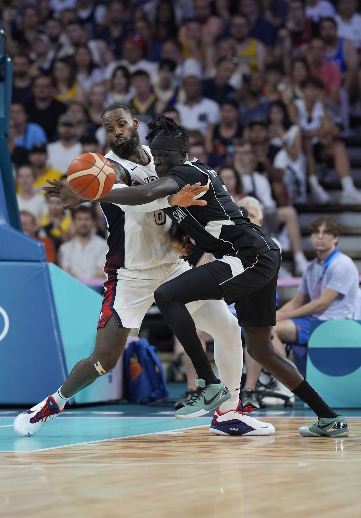  United States guard Lebron James (6) and South Sudan small forward Nuni Omot (5) fight for a loose ball in the fourth quarter during the Paris 2024 Olympic Summer Games at Stade Pierre-Mauroy