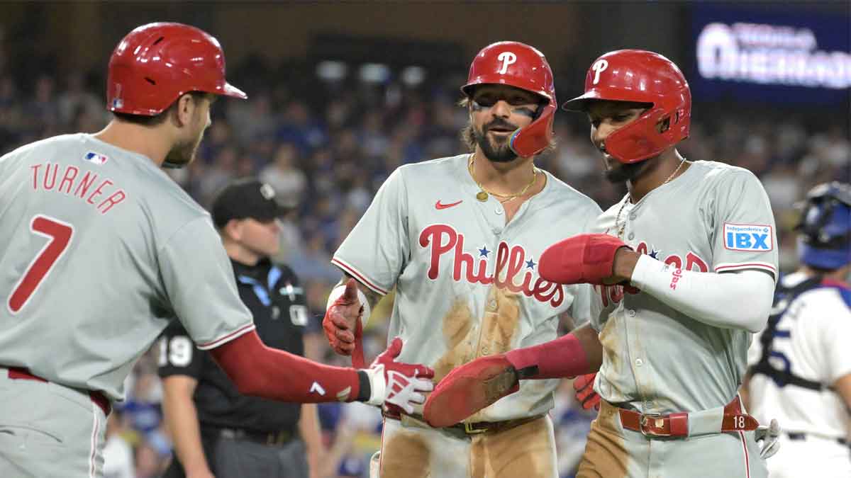     Philadelphia Phillies left fielder Austin Hays (9) and center fielder Johan Rojas (18) are greeted by shortstop Trea Turner (7) after scoring on a double by Philadelphia Phillies designated hitter Kyle Schwarber (12) in the fifth inning at Dodger Stadium.