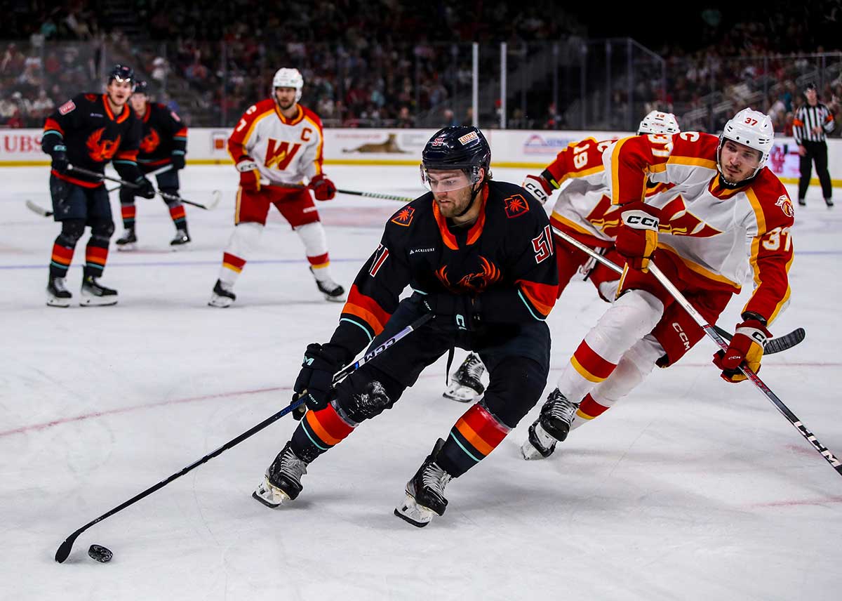 Coachella Valley forward Shane Wright (51) takes the puck around Calgary defenseman Yan Kuznetsov (37) to look for a scoring opportunity during the first period of Game 3 of the Pacific Division semifinals at Acrisure Arena in Palm Desert, Calif., Wednesday, May 8, 2024.