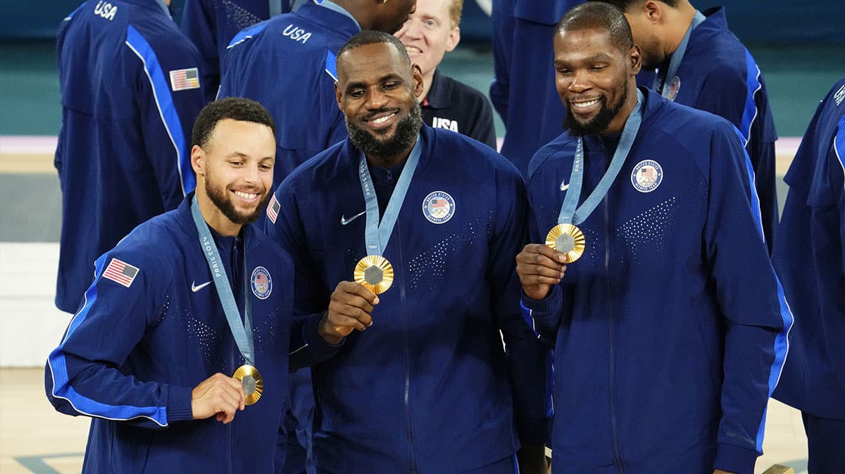 United States shooting guard Stephen Curry (4) and guard LeBron James (6) and guard Kevin Durant (7) celebrate with their gold medals on the podium after defeating France in the men's basketball gold medal game during the Paris 2024 Olympic Summer Games at Accor Arena.