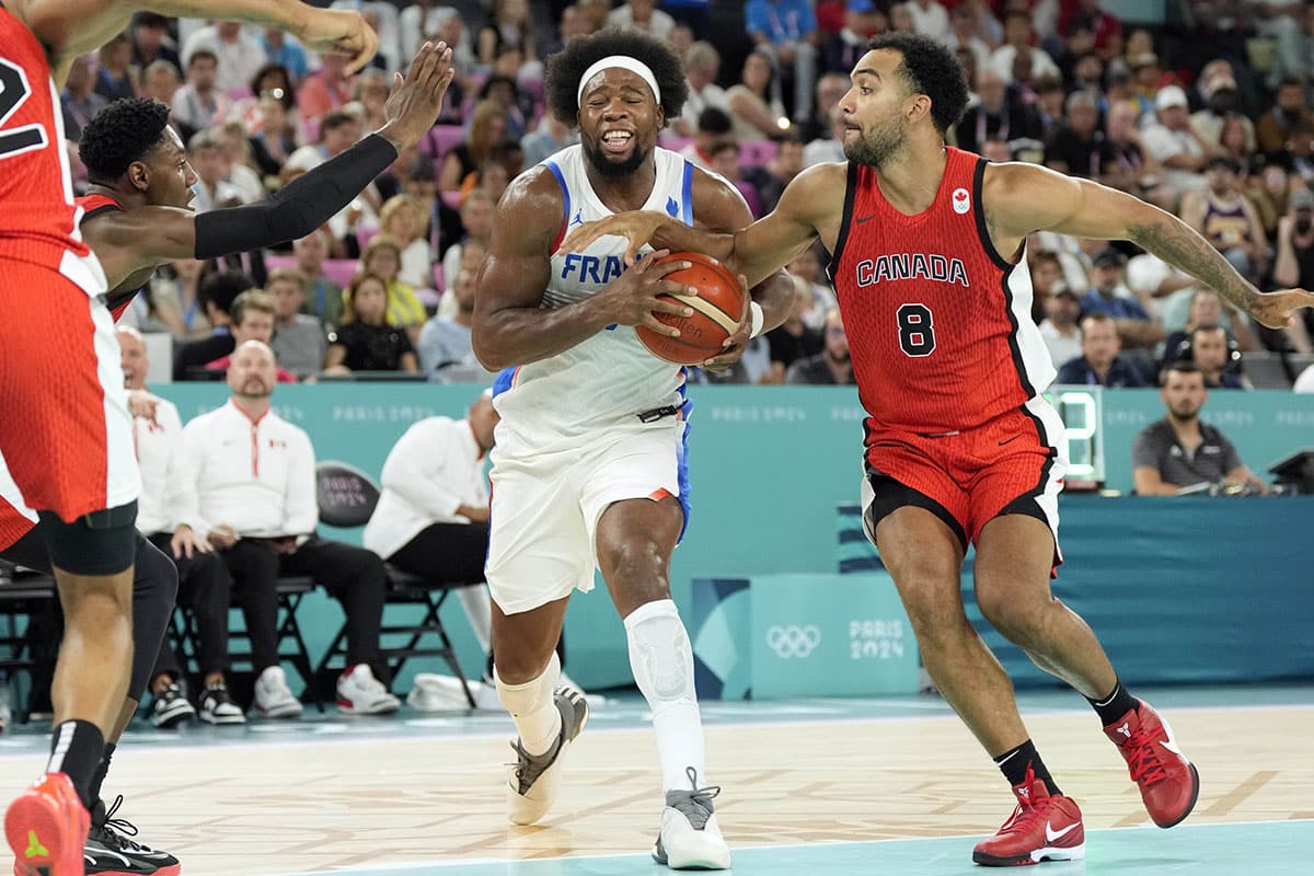 France power forward Guerschon Yabusele (7) controls the ball against Canada centre Trey Lyles (8) and small forward RJ Barrett (9) in the third quarter in a men’s basketball quarterfinal game during the Paris 2024 Olympic Summer Games at Accor Arena.