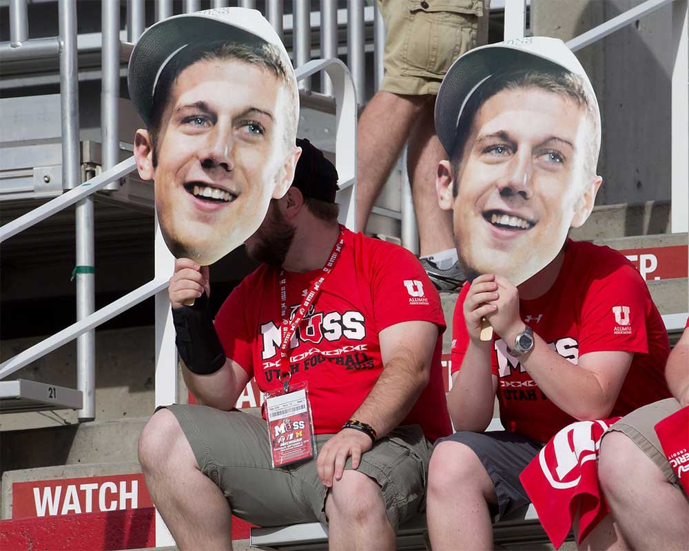 Utah Utes fans hold up cutouts of the face of former Utah Utes and current San Francisco 49er's quarterback Alex Smith prior to the game against head coach Jim Harbaugh and his Michigan Wolverines at Rice-Eccles Stadium.