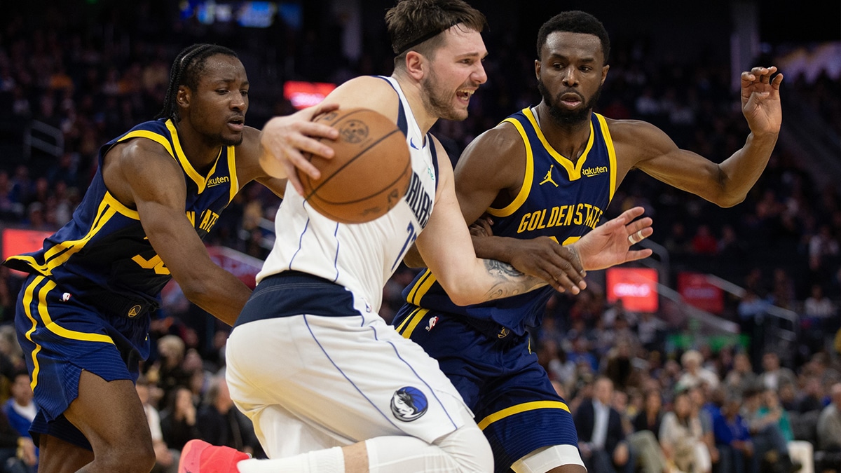 Dec 30, 2023; San Francisco, California, USA; Golden State Warriors forwards Jonathan Kuminga (00) and Andrew Wiggins (22) defended against Dallas Mavericks forward Luka Doncic (77) during the fourth quarter at Chase Center.