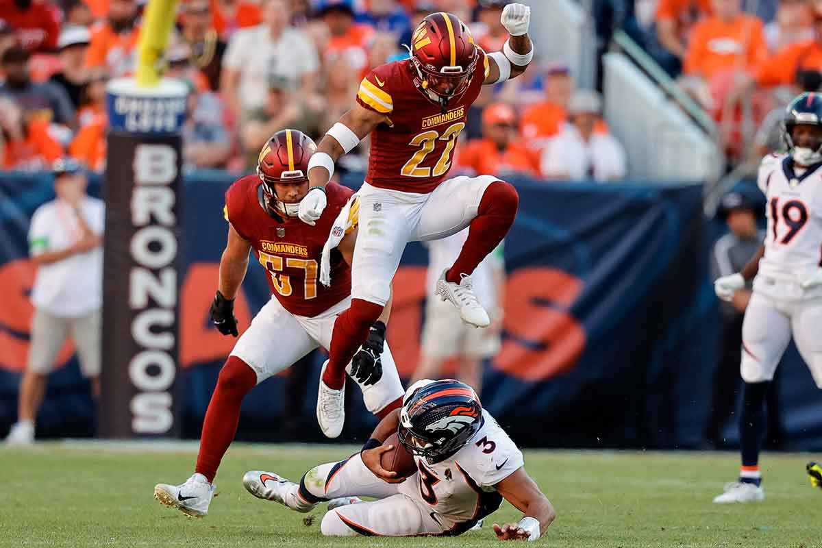 Denver Broncos quarterback Russell Wilson (3) slides for a first down against Washington Commanders safety Darrick Forrest (22) and linebacker Cody Barton (57) in the fourth quarter at Empower Field at Mile High. 