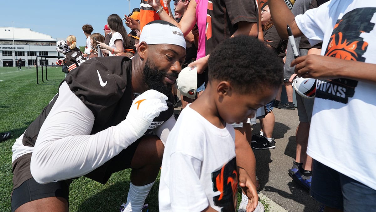 Cleveland Browns defensive end Za'Darius Smith (99) signs a shirt for 4 year old Deamondre Conner Jr. after practice at the Browns training facility in Berea, Ohio.