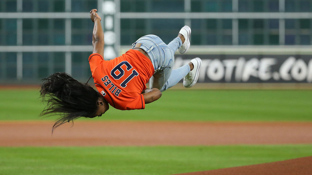 Houston native and Olympic gymnastics gold medalist Simone Biles performs a flip before throwing out a ceremonial first pitch prior to game two of the 2019 World Series between the Houston Astros and the Washington Nationals at Minute Maid Park.