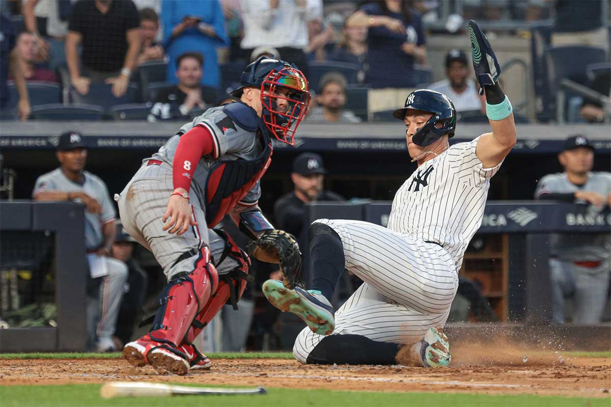 New York Yankees center fielder Aaron Judge (99) beats the throw to score a run behind Minnesota Twins catcher Christian Vazquez (8) during the third inning at Yankee Stadium.