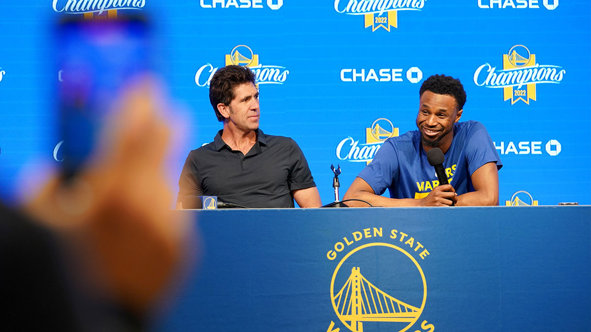 Golden State Warriors forward Andrew Wiggins (22) sits next to general manager Bob Myers during a pregame press conference against the Oklahoma City Thunder at Chase Center.