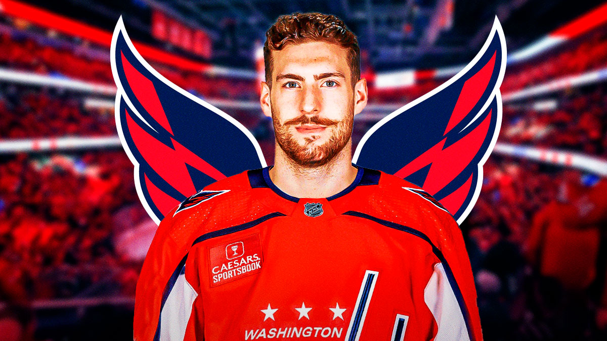 Pierre-Luc Dubois looking happy in a Washington Capitals jersey, Washington Capitals logo, hockey rink in background