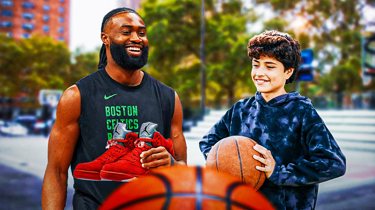 Celtics star Jaylen Brown smiling while handing a pair of sneakers to a happy kid