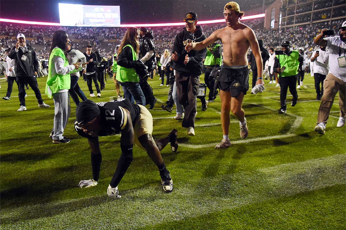 Colorado Buffaloes wide receiver Travis Hunter (12) falls in the end zone as he is chased by fans trying to leave the field following an overtime win against the Baylor Bears at Folsom Field.