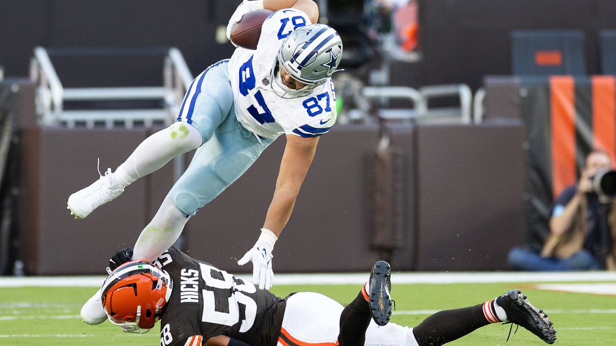 Dallas Cowboys tight end Jake Ferguson (87) falls over Cleveland Browns linebacker Jordan Hicks (58) as he is tackled around his ankle during the third quarter at Huntington Bank Field.