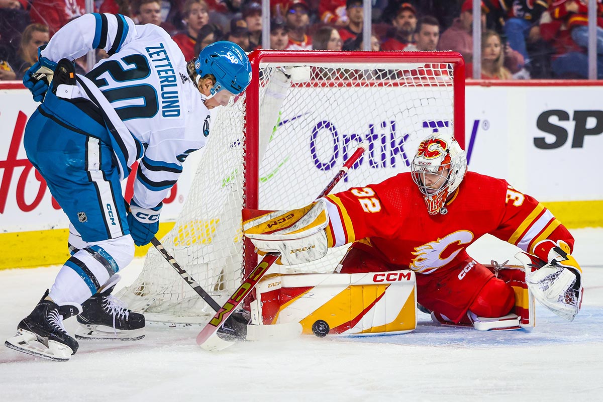 Calgary Flames goaltender Dustin Wolf (32) makes a save against San Jose Sharks left wing Fabian Zetterlund (20) during the first period at Scotiabank Saddledome