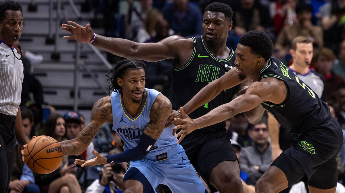 Memphis Grizzlies guard Ja Morant (12) looks to pass the ball as he is boxed in the corner by New Orleans Pelicans forward Zion Williamson (1) and forward Herbert Jones (5) during the first half at the Smoothie King Center.