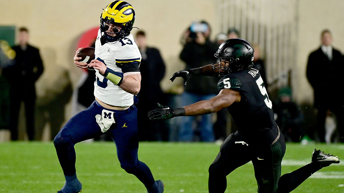 Michigan Wolverines quarterback Jack Tuttle (13) runs away from Michigan State Spartans linebacker Jordan Hall (5) in the fourth quarter at Spartan Stadium.