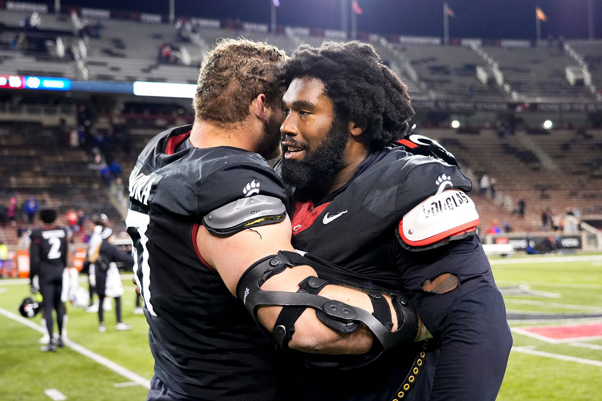 Cincinnati Bearcats offensive lineman Luke Kandra (67), left, and Cincinnati Bearcats defensive end Jowon Briggs (0) embrace after losing the NCAA college football game between the Cincinnati Bearcats and Kansas Jayhawks.