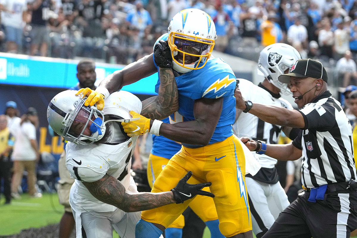 Los Angeles Chargers wide receiver Joshua Palmer (5) and Las Vegas Raiders safety Marcus Epps (1) fight as back judge Terrence Miles (111) intervenes in the second half at SoFi Stadium.