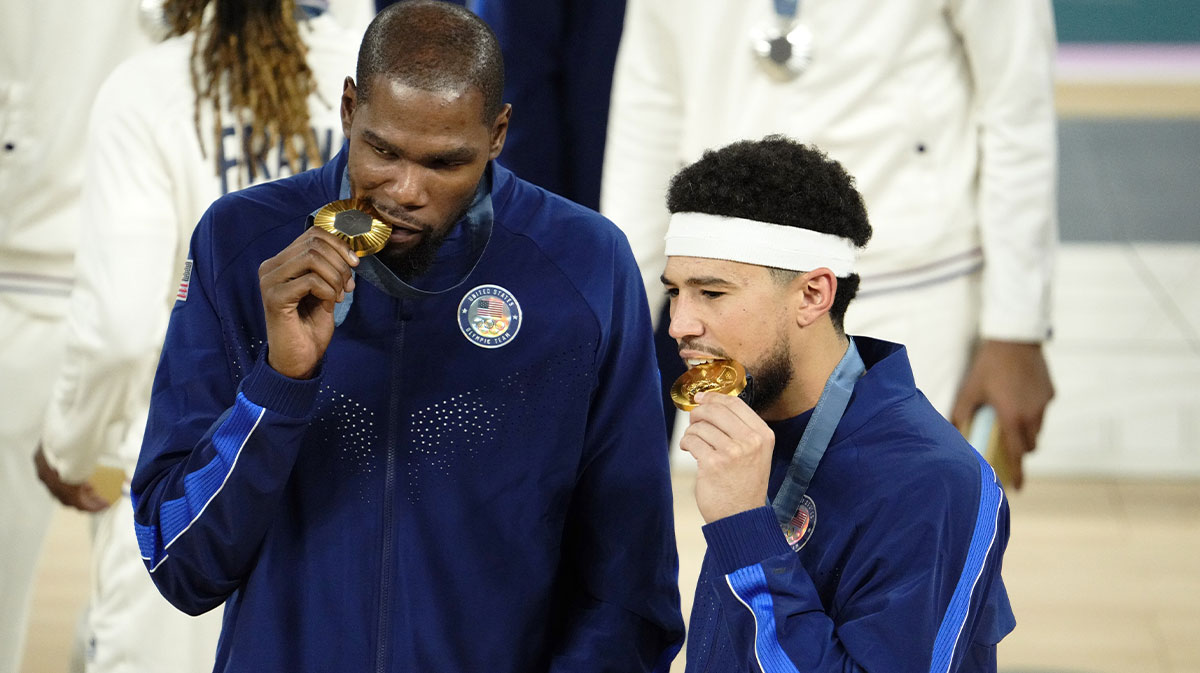 United States guard Kevin Durant (7) and guard Devin Booker (15) celebrate with their gold medals on the podium after defeating France in the men's basketball gold medal game during the Paris 2024 Olympic Summer Games at Accor Arena.