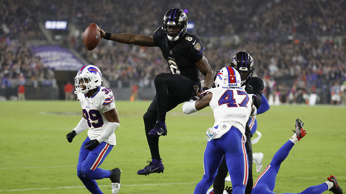 Sep 29, 2024; Baltimore, Maryland, USA; Baltimore Ravens quarterback Lamar Jackson (8) scores a touchdown as Buffalo Bills safety Damar Hamlin (3) and Bills cornerback Christian Benford (47) defend during the third quarter at M&T Bank Stadium.