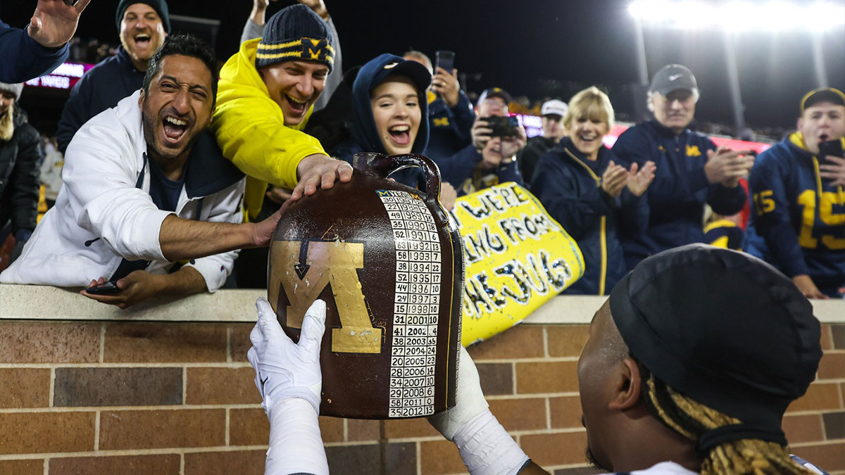 Michigan Wolverines fans celebrates with the little brown jug after the game against the Minnesota Golden Gophers at Huntington Bank Stadium.