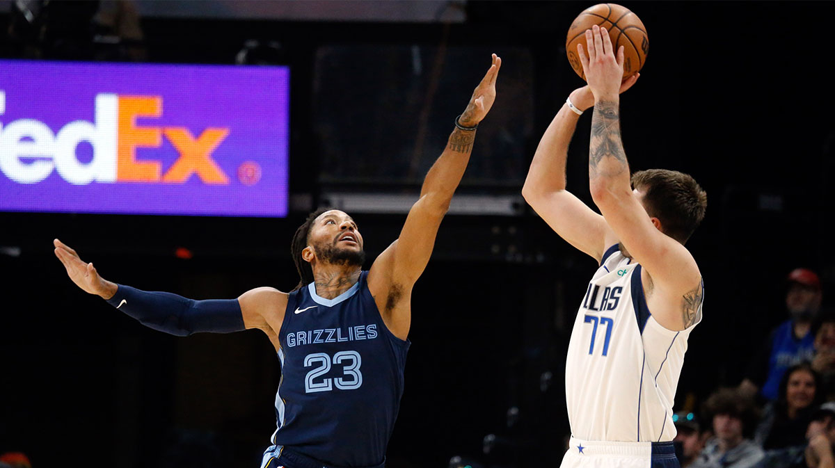     Dallas Mavericks guard Luka Doncic (77) shoots a three-pointer as Memphis Grizzlies guard Derrick Rose (23) looks on during the second half at FedExForum.