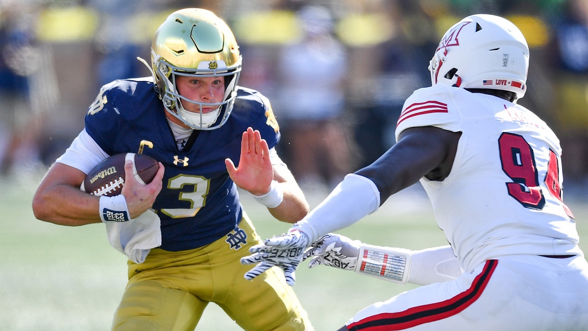 Notre Dame football Fighting Irish quarterback Riley Leonard (13) runs the ball as Miami Redhawks defensive end Josh Lukusa (94) defends in the second quarter at Notre Dame Stadium.
