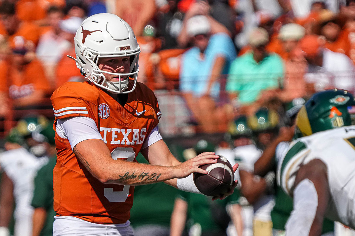college football player Quinn Ewers handing the football off on Texas