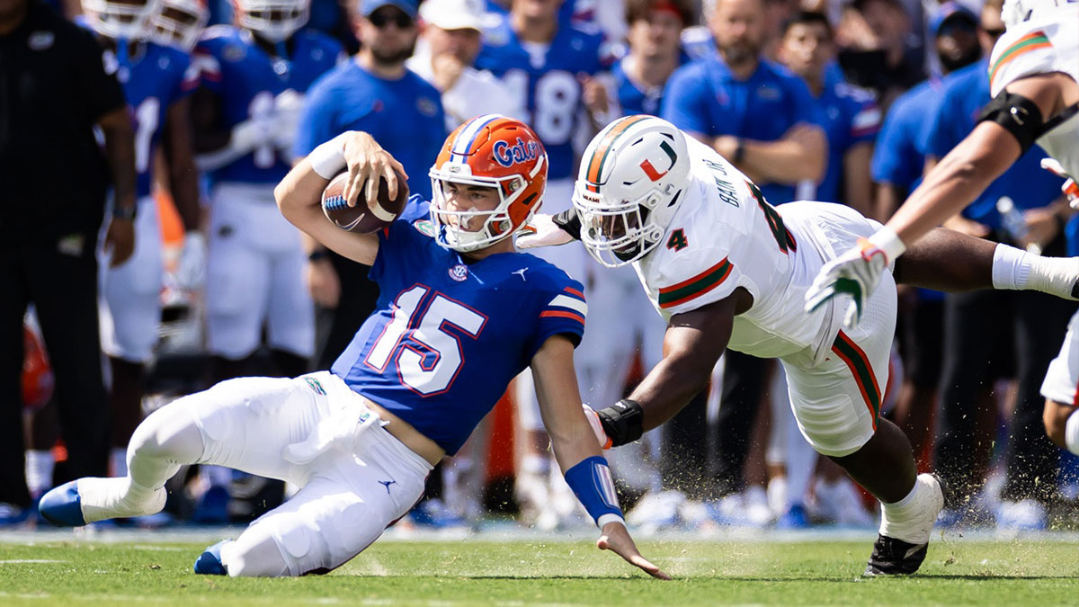 Florida Gators quarterback Graham Mertz (15) slides for a first down while Miami Hurricanes defensive lineman Rueben Bain Jr. (4) attempts to tackle during the first half at Ben Hill Griffin Stadium.