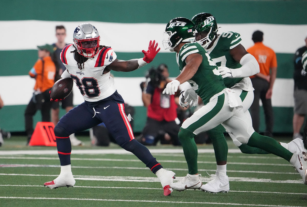 New England Patriots running back Rhamondre Stevenson (38) runs away from New York Jets linebacker Chazz Surratt (55) and defensive end Jalyn Holmes (97) at MetLife Stadium.