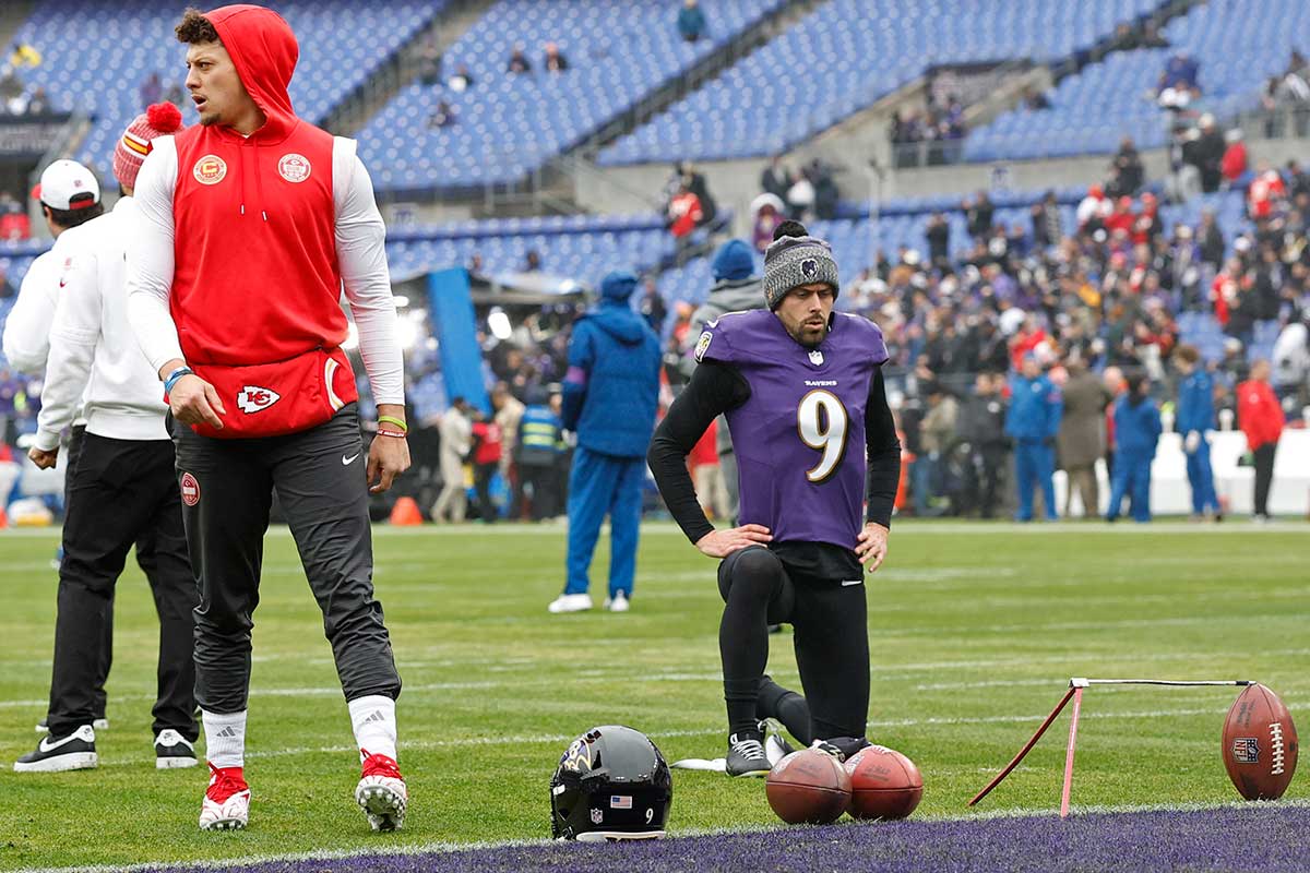 Kansas City Chiefs quarterback Patrick Mahomes (L) stands on the field prior to warmup as Baltimore Ravens place kicker Justin Tucker (9) attempts to take warmup kicks before their game in the AFC Championship football game at M&T Bank Stadium.