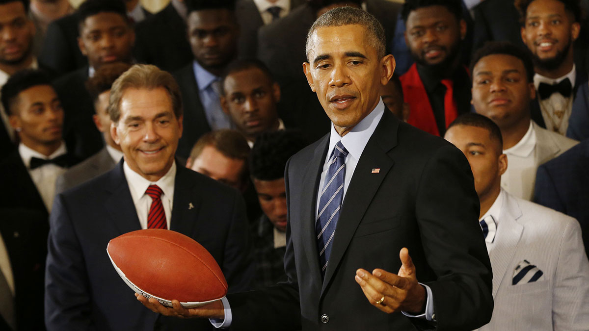 President Barack Obama holds an honorary game ball presented by Alabama Crimson Tide head coach Nick Saban (left) during a ceremony honoring the 2015 national champion Crimson Tide in the East Room at the White House