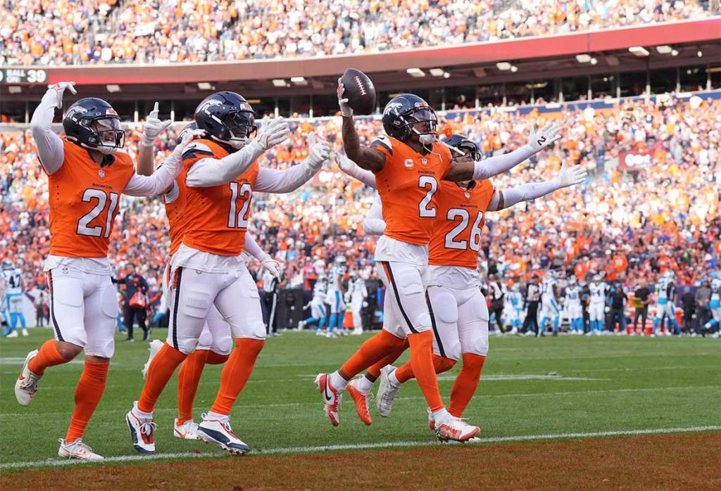 Denver Broncos cornerback Pat Surtain II (2) celebrates his interception with cornerback Riley Moss (21) and linebacker Kwon Alexander (12) and safety Devon Key (26) in the third quarter against the Carolina Panthers at Empower Field at Mile High.