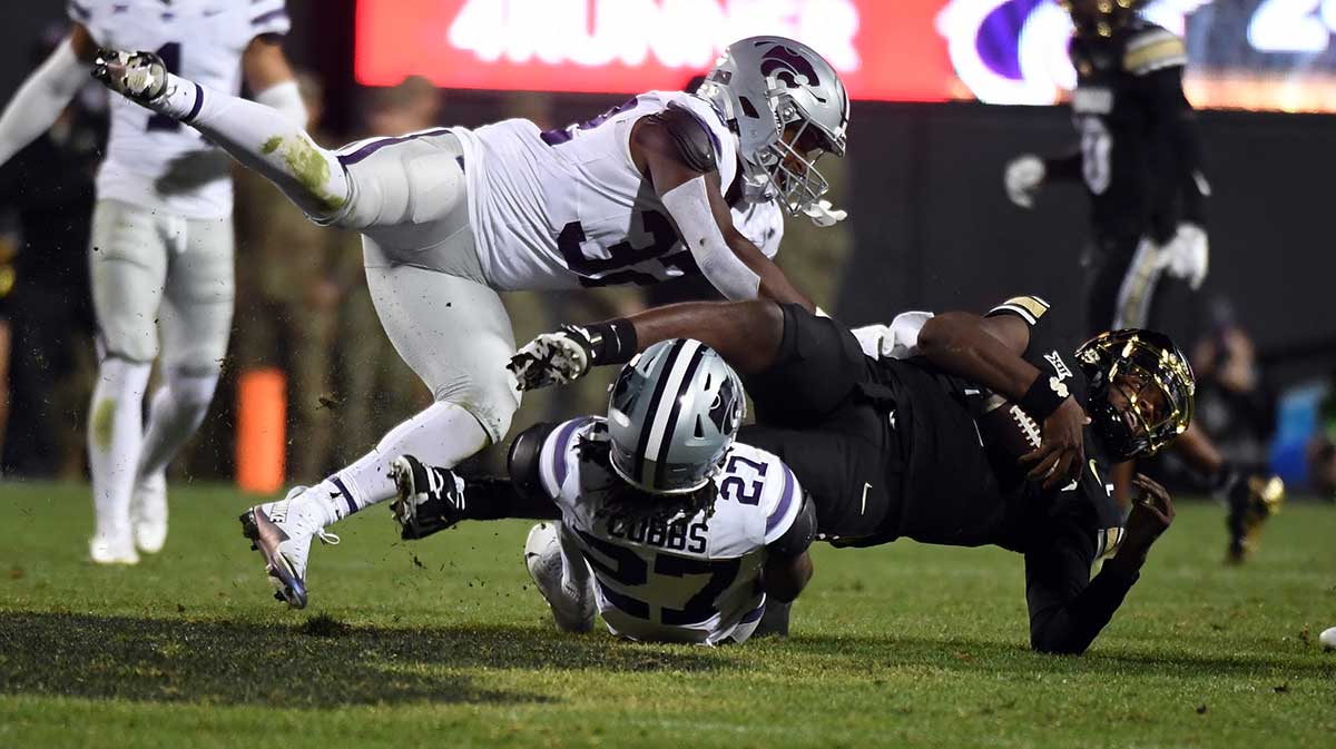 Colorado Buffaloes quarterback Shedeur Sanders (2) is tackled by Kansas State Wildcats safety Daniel Cobbs (27) and linebacker Desmond Purnell (32) after a run during the second half at Folsom Field.