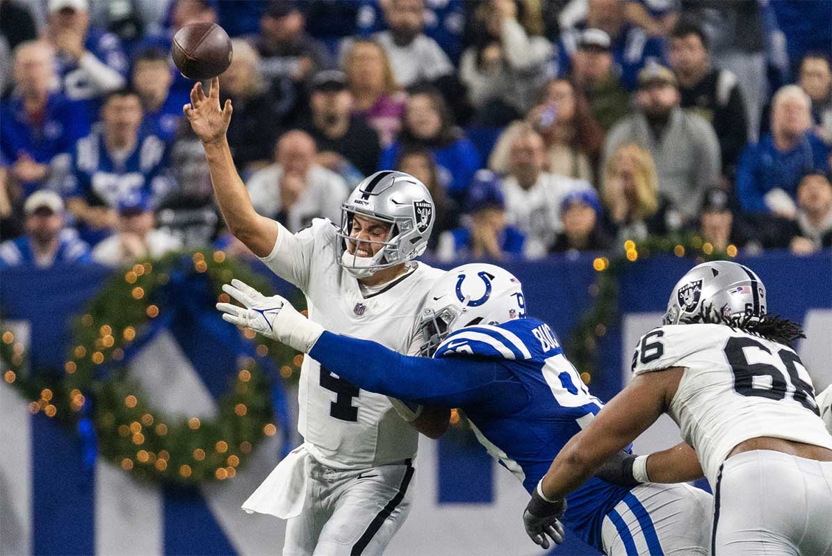 Las Vegas Raiders quarterback Aidan O'Connell (4) passes the ball while Indianapolis Colts defensive tackle DeForest Buckner (99) defends in the first half at Lucas Oil Stadium.
