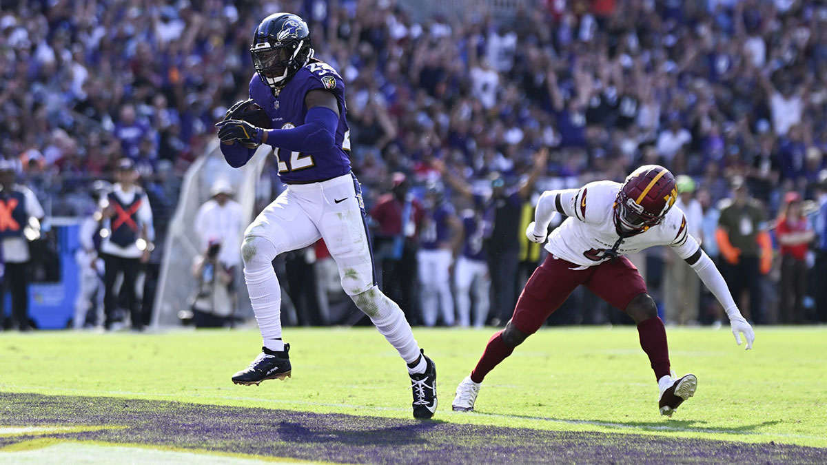 Baltimore Ravens running back Derrick Henry (22) rushes by Washington Commanders cornerback Mike Sainristil (0) for a second half touchdown at M&T Bank Stadium.