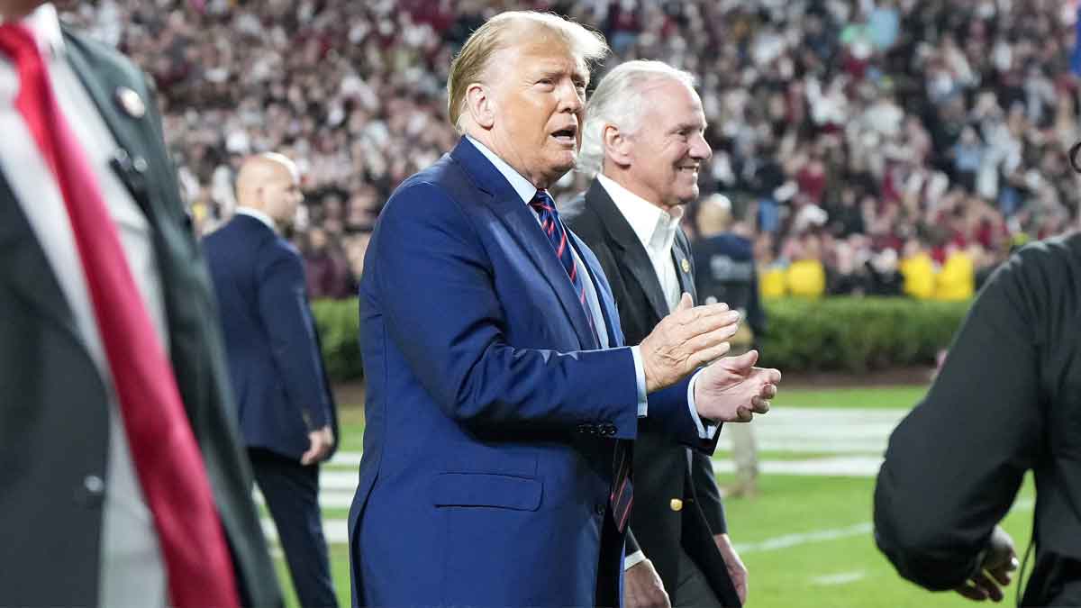 Former President Donald Trump (middle) walks with South Carolina Governor Henry McMaster during a game between the South Carolina Gamecocks and the Clemson Tigers at Williams-Brice Stadium.