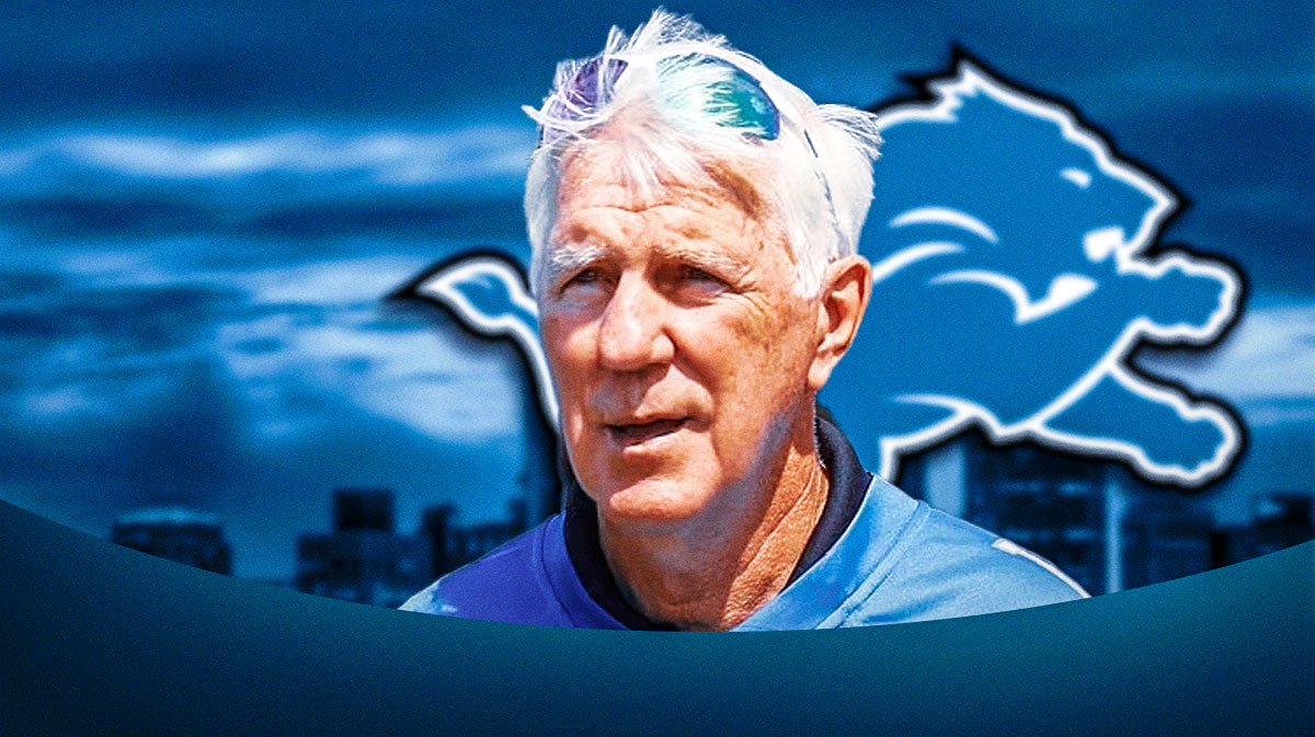 Former Lions quarterback and assistant coach Greg Landry next to the Lions logo