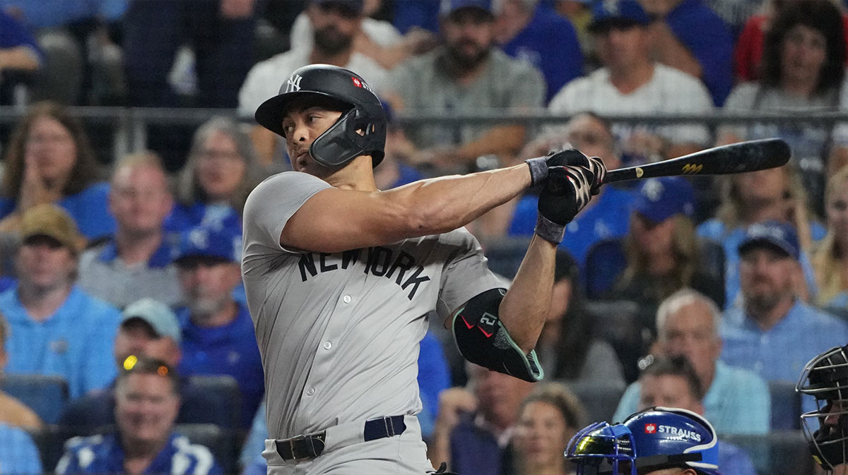 New York Yankees designated hitter Giancarlo Stanton (27) hits an RBI single during the sixth inning against the Kansas City Royals during game four of the ALDS for the 2024 MLB Playoffs at Kauffman Stadium.