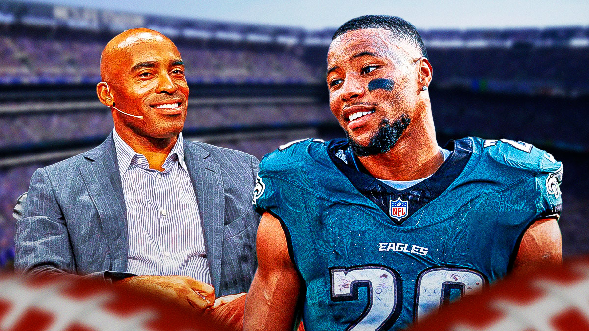 Former New York Giants running back Tiki Barber, smiling with a photo of Saquon Barkley next to him in a Philadelphia Eagles jersey.