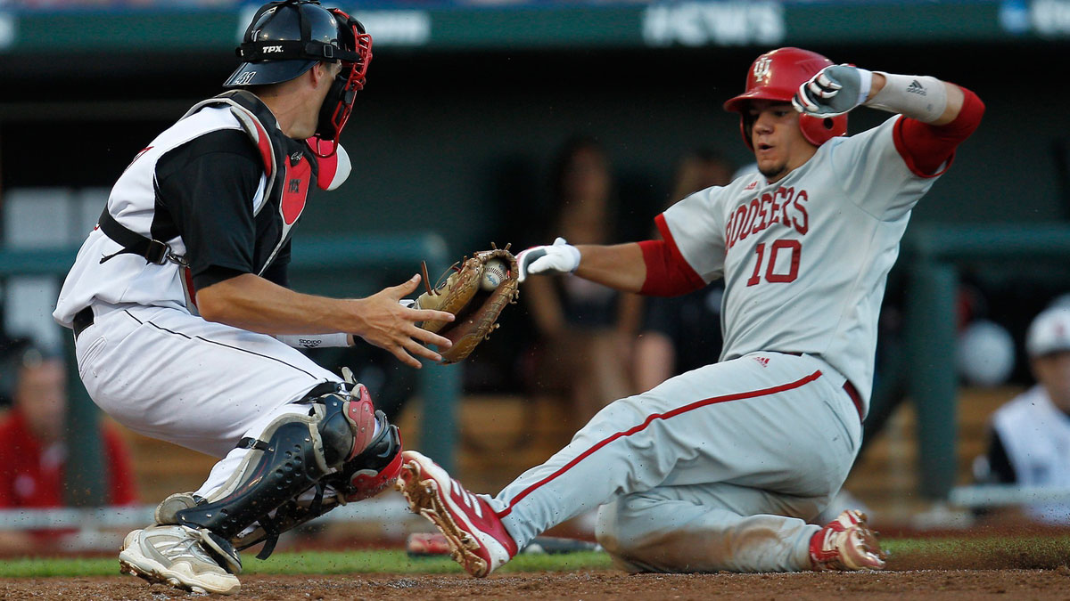 Indiana Hoosiers runner Kyle Schwarber (10) is tagged out in the third inning by the Louisville Cardinals catcher Shane Crain (41) during the College World Series game at TD Ameritrade Park.