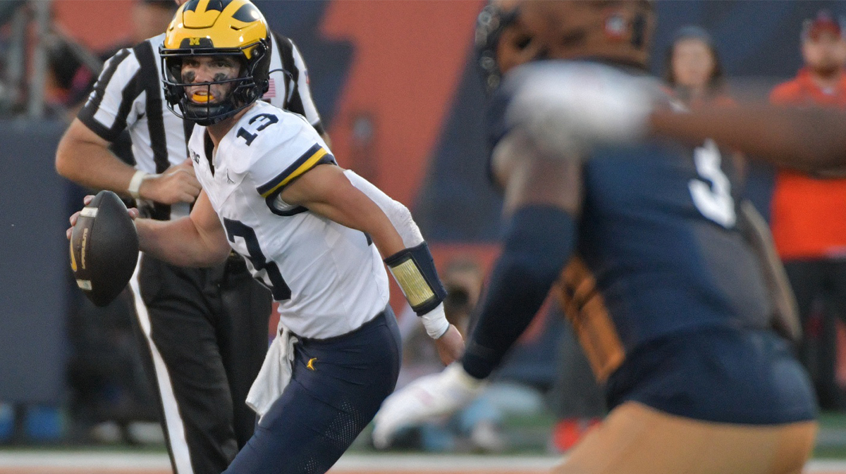 Michigan Wolverines quarterback Jack Tuttle (13) runs with the ball against Illinois Fighting Illini linebacker Alec Bryant (3) during the second half at Memorial Stadium.