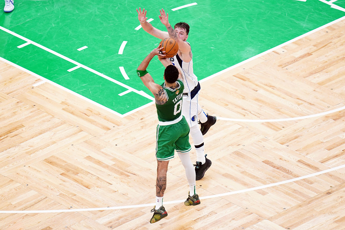 Boston Celtics forward Jayson Tatum (0) shoots a three point shot against Dallas Mavericks guard Luka Doncic (77) in the second quarter during game five of the 2024 NBA Finals at TD Garden. 