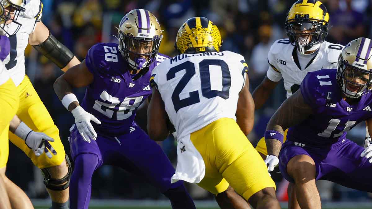 Washington Huskies linebacker Khmori House (28) and linebacker Alphonzo Tuputala (11) tackle Michigan Wolverines running back Kalel Mullings (20) during the first quarter at Alaska Airlines Field at Husky Stadium.