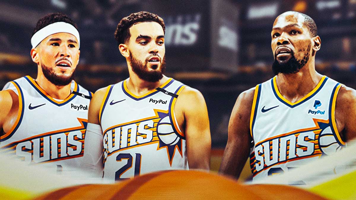 Phoenix Suns guard Devin Booker, Tyus Jones, are looking at forward Kevin Durant with a background of the Suns logo