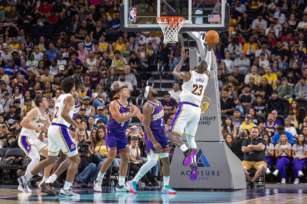 Los Angeles Lakers forward LeBron James (23) shoots a layup over Phoenix Suns guard Devin Booker (1) during the first half at Acrisure Arena.